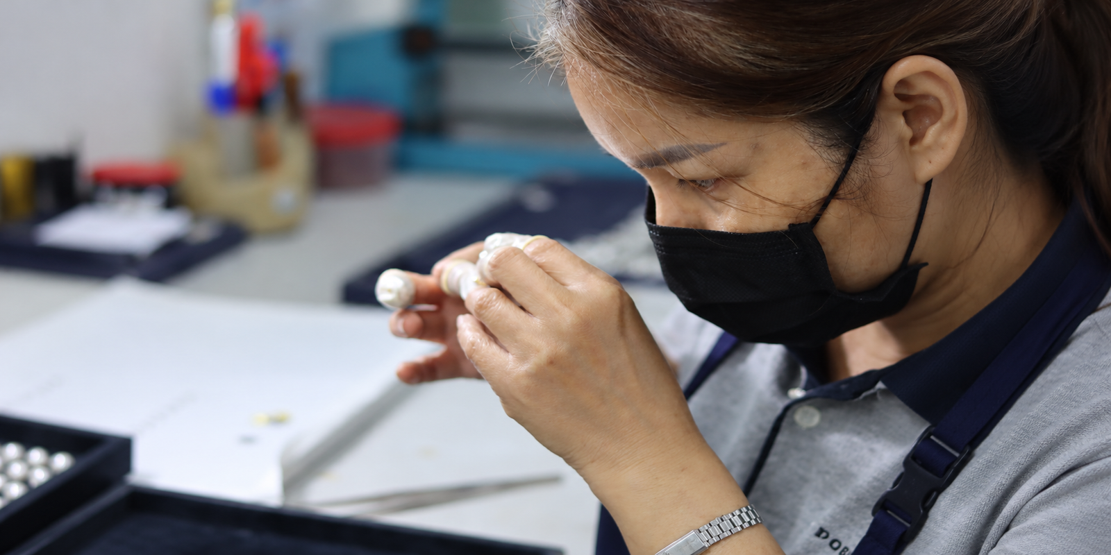 Jewelry artisan closely examining a small jewelry component by hand during the custom jewelry manufacturing quality inspection process.
