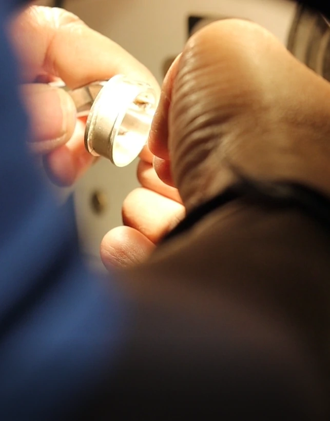 Close-up of a skilled jewelry artisan carefully working on a metal ring by hand during the custom jewelry manufacturing process.