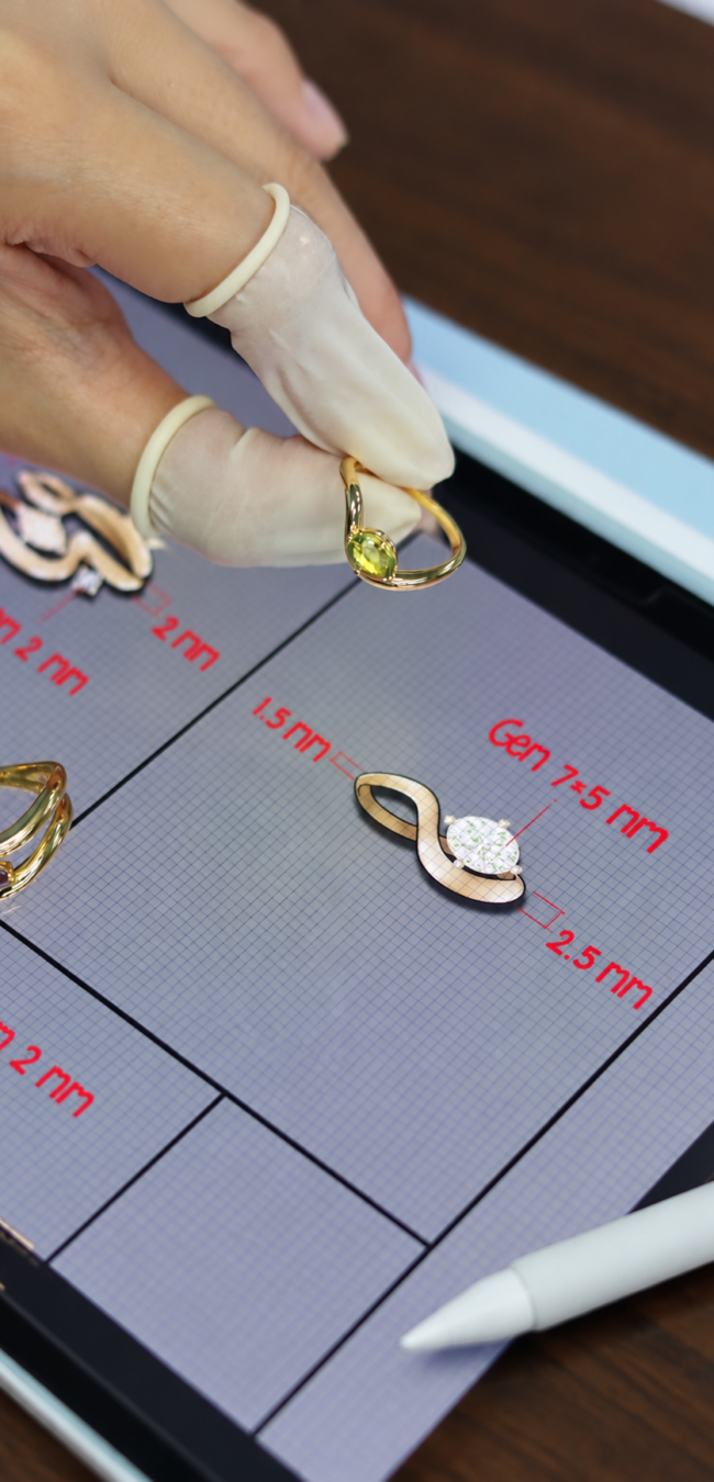 Jewelry designer holding a gold ring with a green gemstone above a digital tablet displaying custom ring designs, gemstone sizes, and technical measurements.
